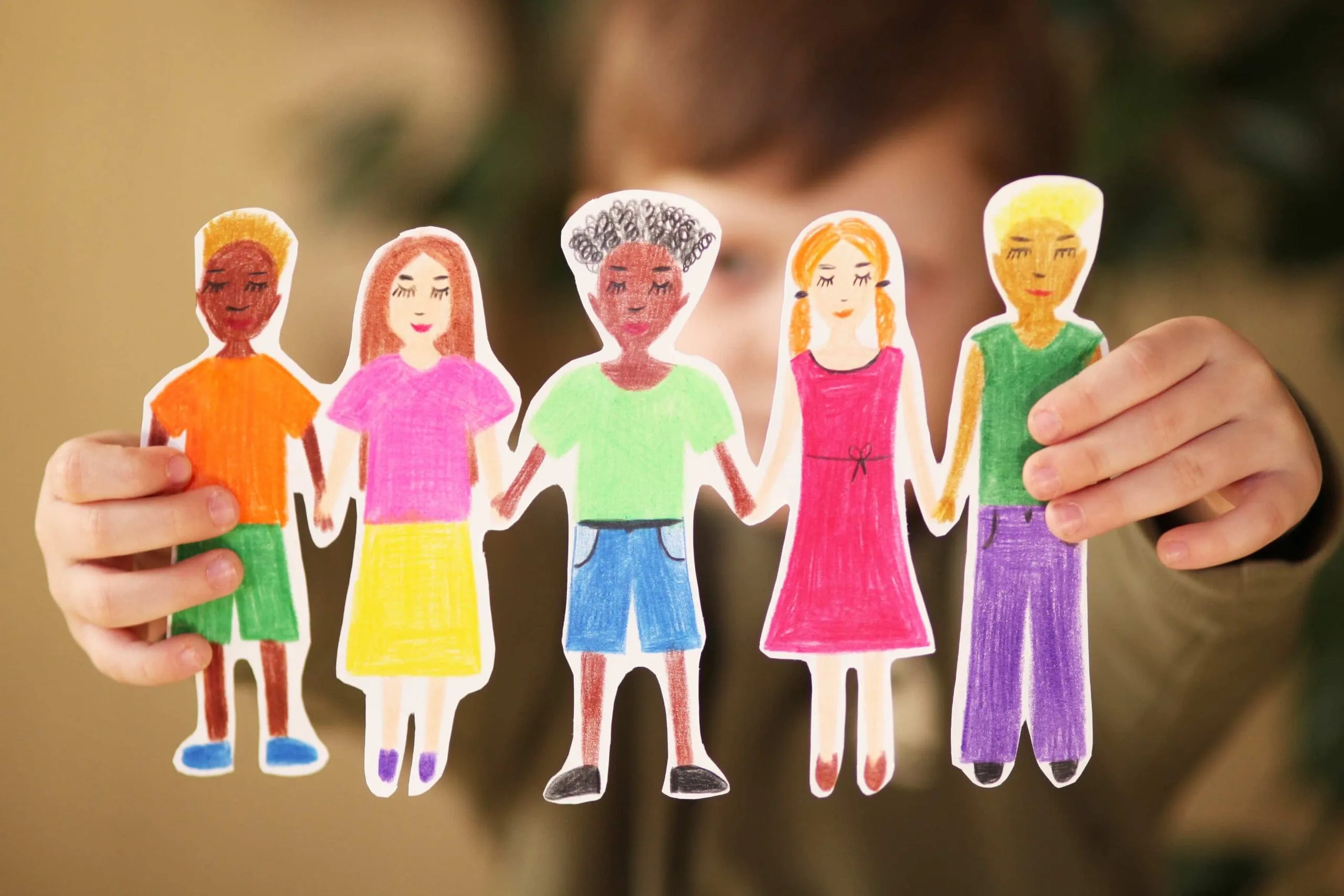 A child holding a paper chain of colorful figures