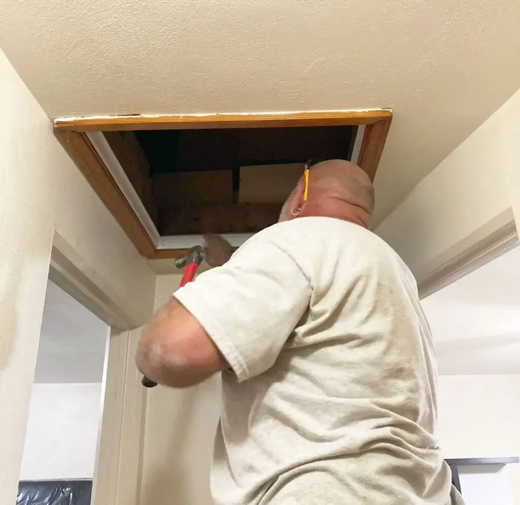 A technician inspecting an attic hatch